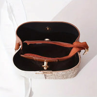 Top view of a beige and brown crossbody bag with zippered compartments on a white surface