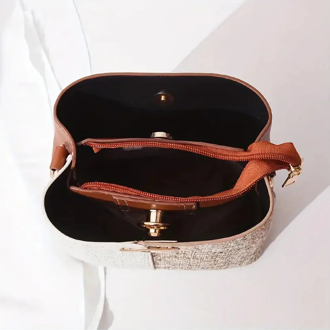 Top view of a beige and brown crossbody bag with zippered compartments on a white surface