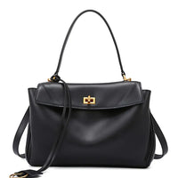 Black leather handbag with gold hardware and top handle on white background