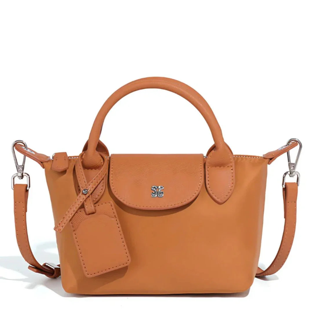 Tan leather mini handbag with top handle, detachable strap, metal logo, and luggage tag