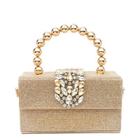 Gold beaded clutch purse with jeweled clasp and round metallic handle on white background