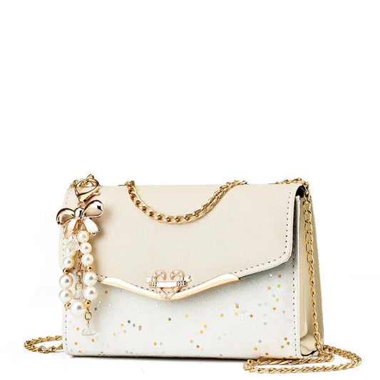 Elegant white handbag with gold chain strap, pearl bow charm, and star accents