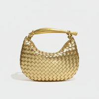Gold woven leather handbag with knot handle on a white background