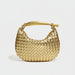 Gold woven leather handbag with knot handle on a white background