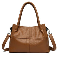 Brown leather handbag with double handles and detachable shoulder strap on white background