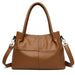 Brown leather handbag with double handles and detachable shoulder strap on white background