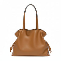 Brown leather tote bag with knotted sides and double handles on a white background
