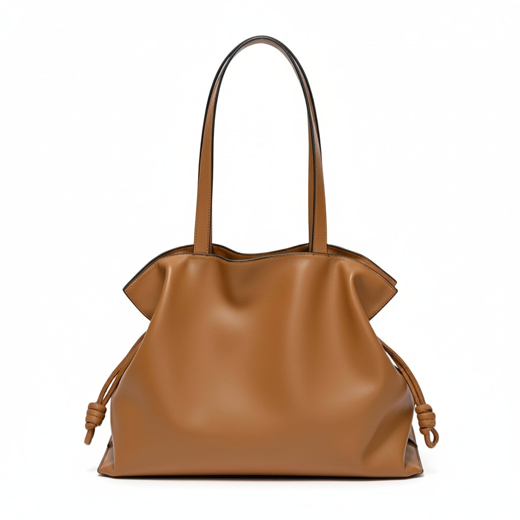 Brown leather tote bag with knotted sides and double handles on a white background