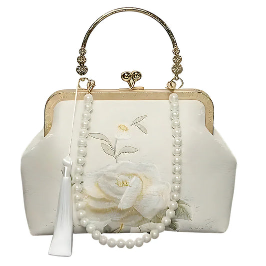 Elegant white floral handbag with gold handle, pearl strap, and tassel accent
