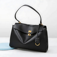 Black leather handbag with gold hardware and top handle on a white background