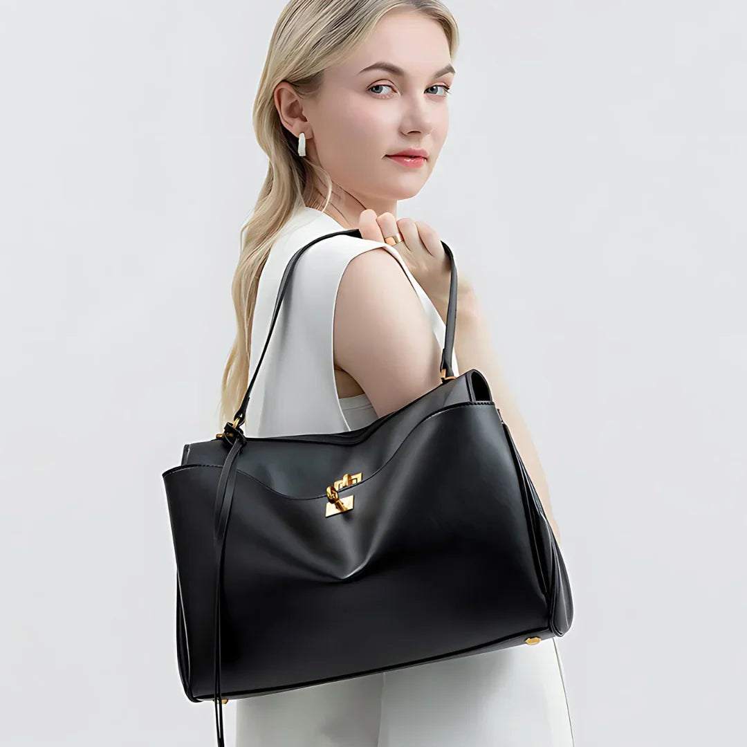 Woman in white outfit holding large black leather handbag with gold hardware