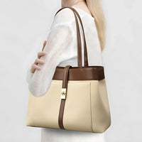 Woman holding a beige and brown leather tote bag with gold clasp, white outfit