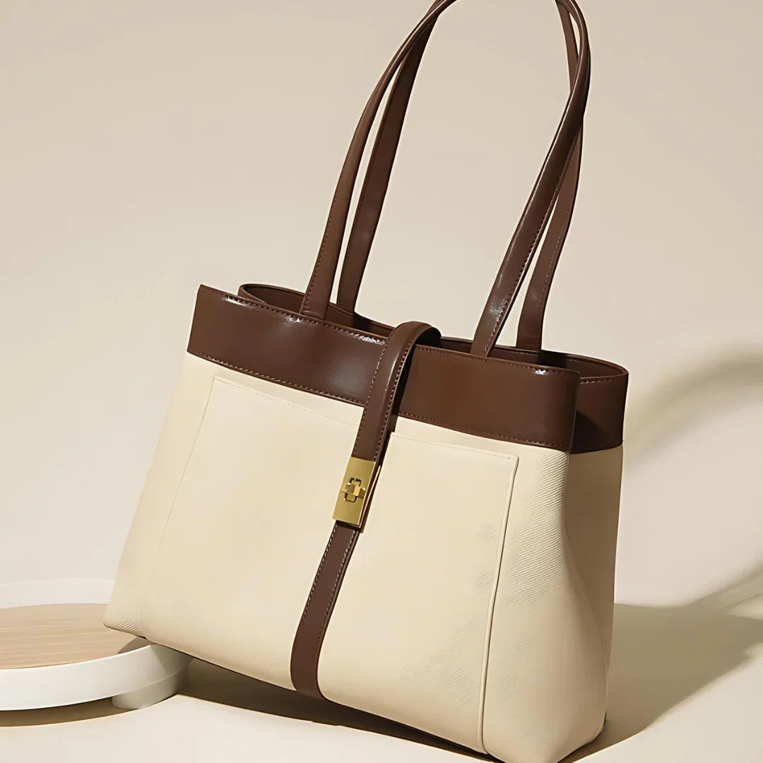 Beige and brown leather tote bag with gold clasp on neutral background