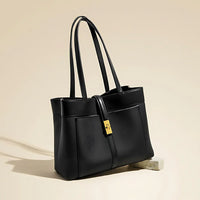 Sleek black leather tote bag with gold clasp on beige background