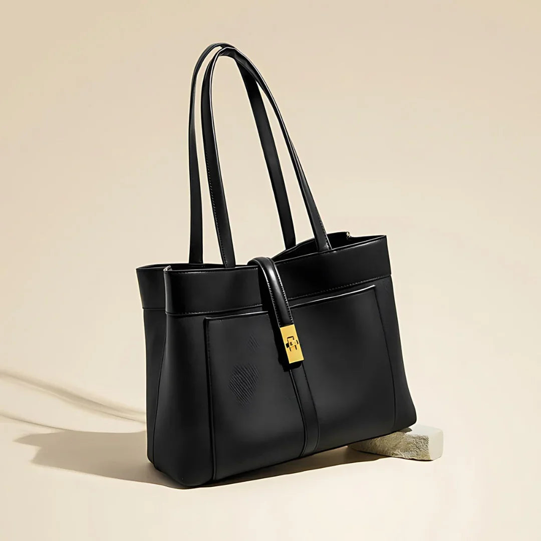 Sleek black leather tote bag with gold clasp on beige background