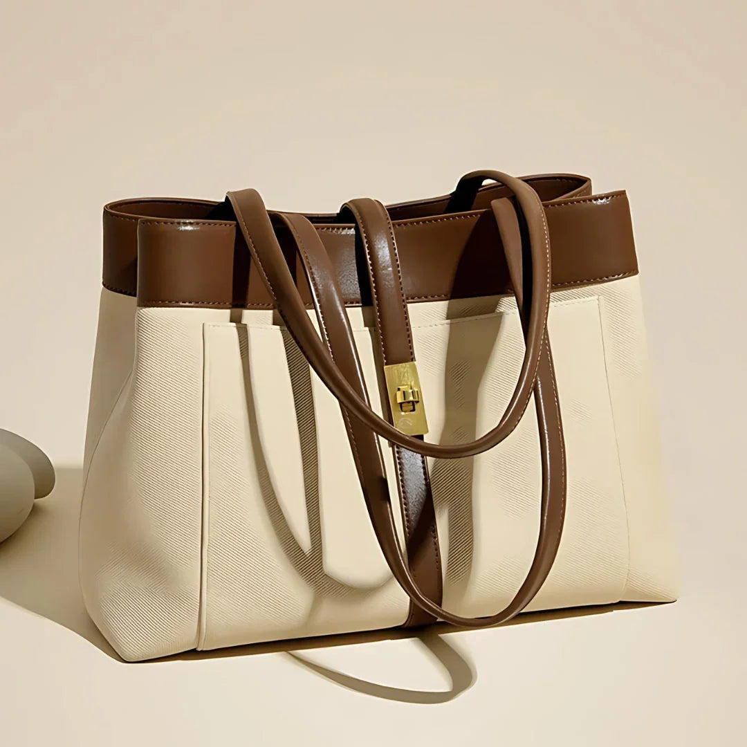 Elegant beige and brown leather tote bag with gold clasp on neutral background