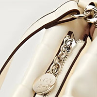 Cream leather handbag with silver zipper and chain detail, fashion accessory close-up