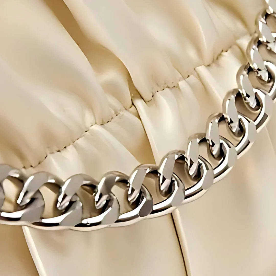 Close-up of a gold chain detail on beige ruched satin fabric
