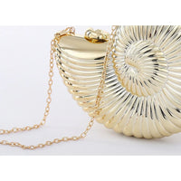Gold seashell clutch purse with shiny metallic finish and gold chain strap on white background