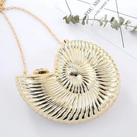 Gold seashell-shaped clutch bag with chain strap on white background, modern accessory