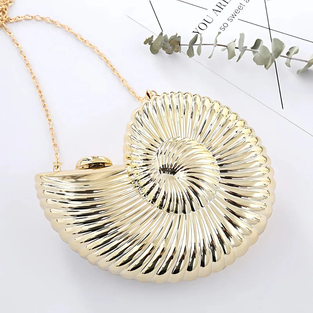 Gold seashell-shaped clutch bag with chain strap on white background, modern accessory