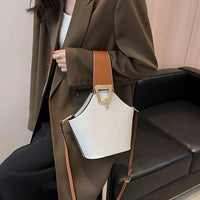 Woman in brown blazer with white and tan designer shoulder bag, modern office setting