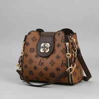 Brown leather designer handbag with gold hardware and monogram pattern on grey background