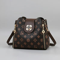 Brown patterned leather shoulder bag with gold accents and zipper details on gray background