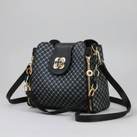 Black designer handbag with gold hardware, geometric pattern, and adjustable strap on gray background