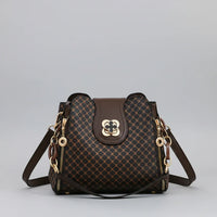 Brown patterned leather handbag with gold hardware and shoulder strap on gray background