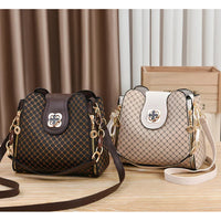 Two patterned shoulder handbags with gold hardware on a wooden table, brown and beige colors