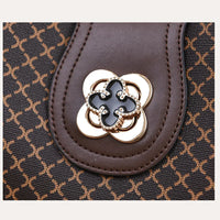Brown leather handbag closeup with gold floral clasp and geometric pattern