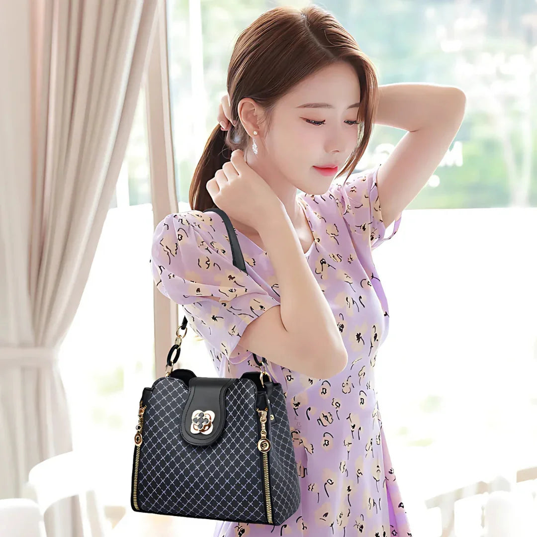 Woman in a lavender dress with a patterned black handbag indoors near window