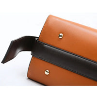 Brown leather handbag with black strap and gold studs on white background