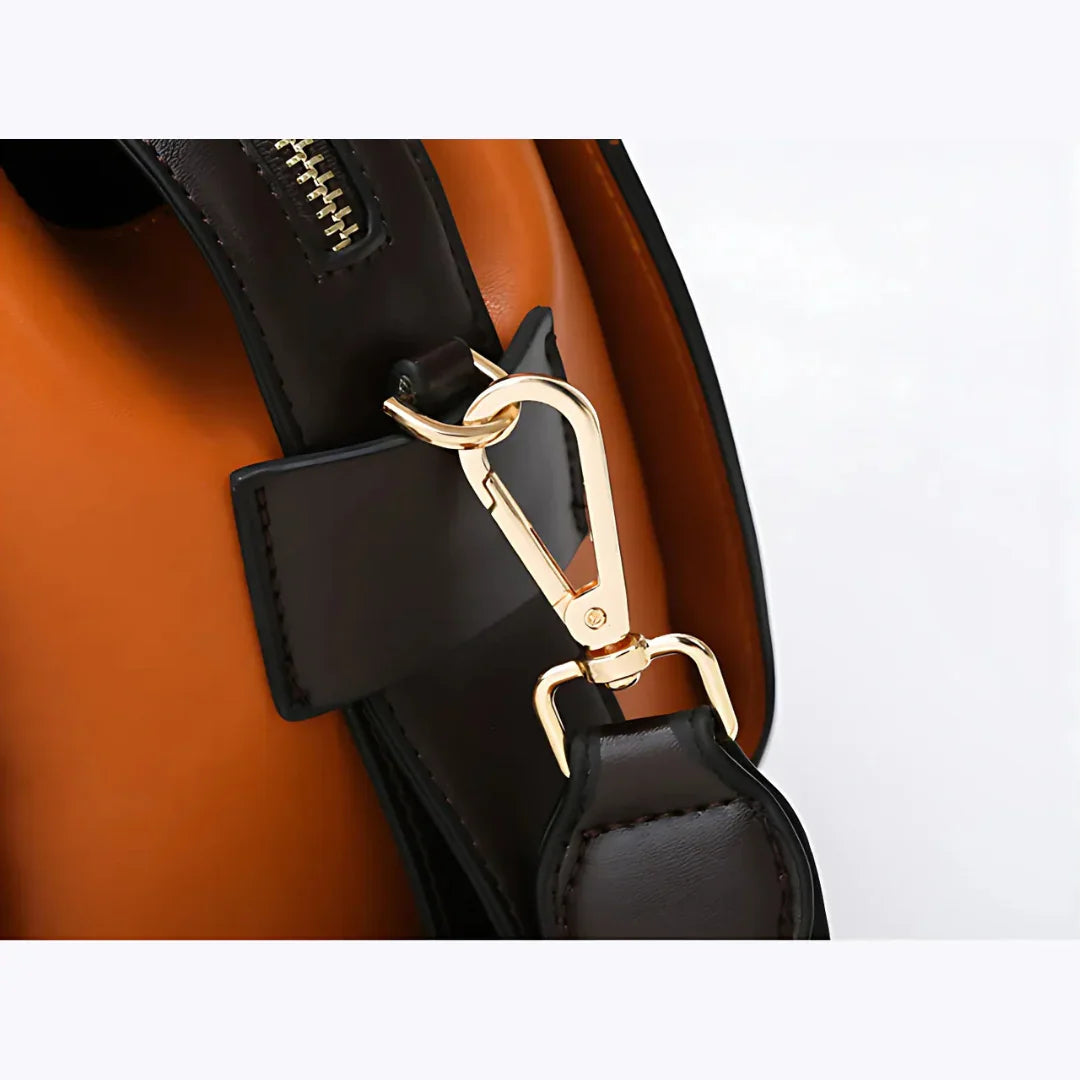 Close-up of gold clasp on brown leather handbag with orange interior