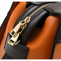 Close-up of brown leather bag with gold zipper and black accents