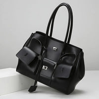 Black leather tote bag with dual handles and front pockets on a white background