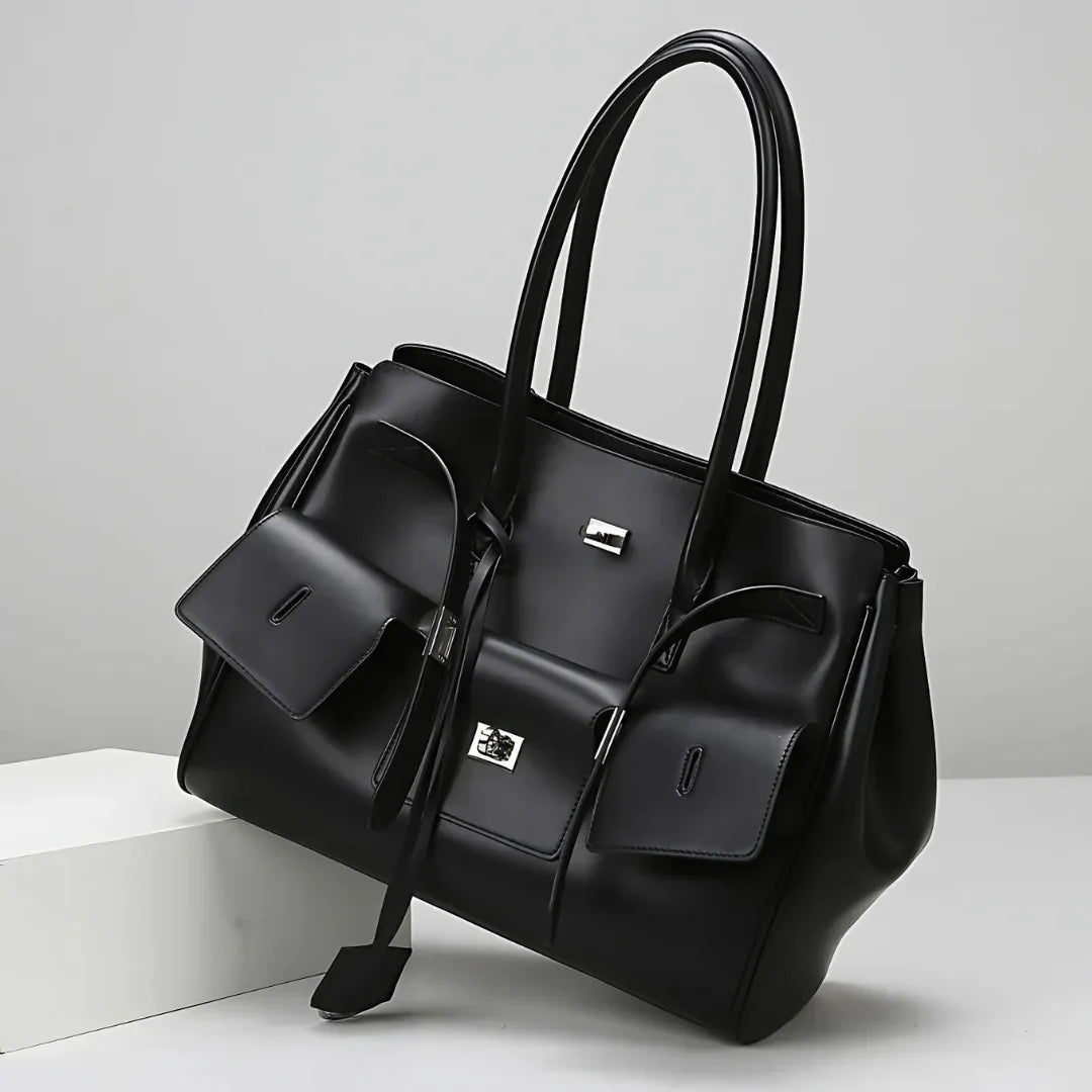 Black leather tote bag with dual handles and front pockets on a white background