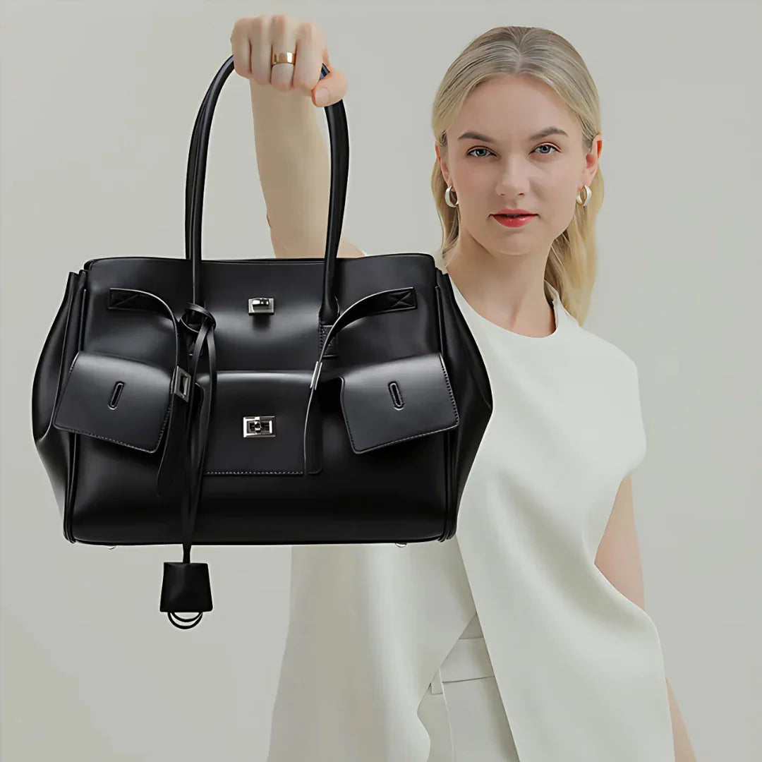 Woman in white top holding large black leather handbag with silver hardware