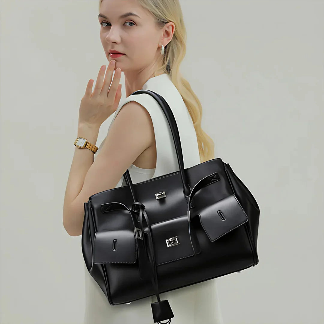 Woman in white dress holding large black leather handbag, fashion accessory