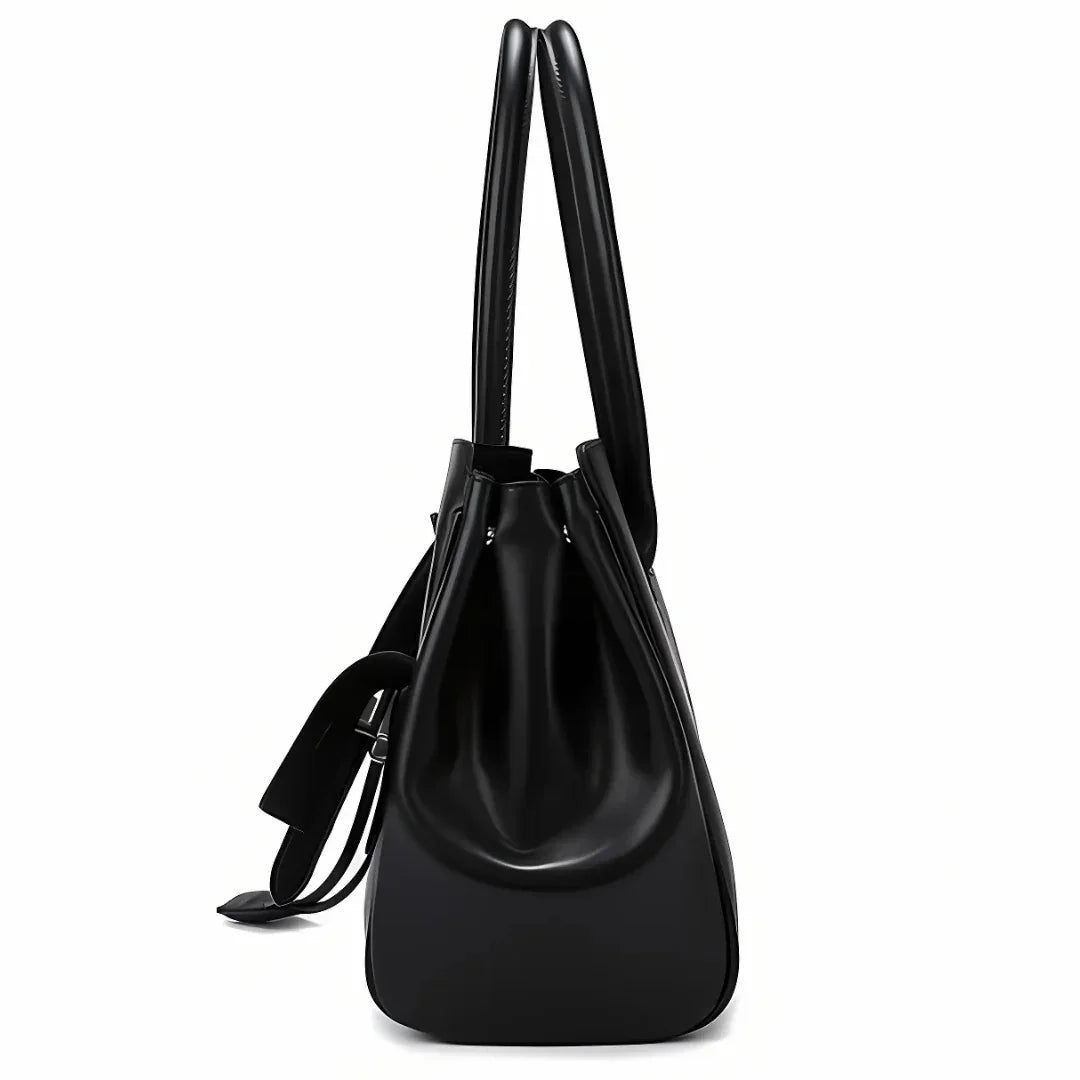 Side view of black leather tote bag with double handles and drawstring detail