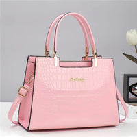 Pink crocodile-pattern faux leather handbag with gold hardware on white table