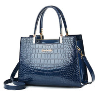 Glossy navy blue crocodile pattern handbag with top handles and gold hardware