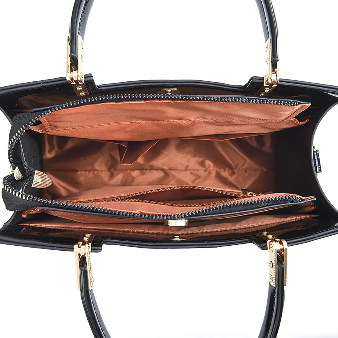 Top view of black handbag with brown interior, multiple zippered compartments and gold hardware