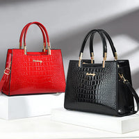 Red and black crocodile pattern handbags with gold handles on white display blocks