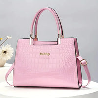 Pink crocodile pattern handbag with gold accents on a white table, flower decor