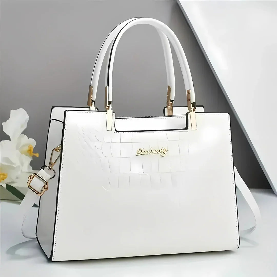 Elegant white leather handbag with gold hardware and double handles on modern background