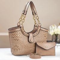 Beige crocodile-embossed handbag with gold chain straps, matching wallet, and strap on table