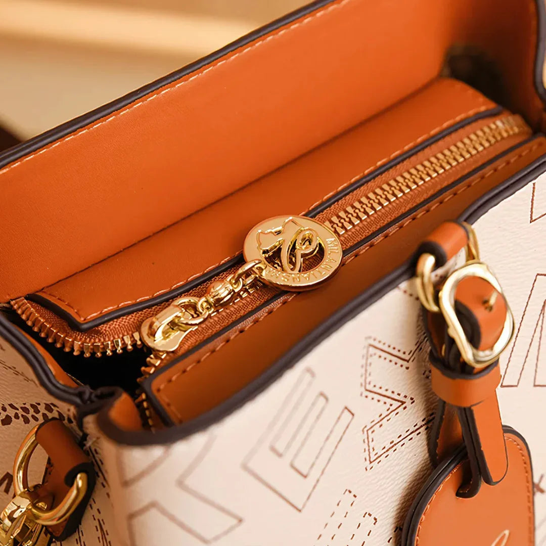 Close-up of tan and cream leather handbag with gold zipper and logo accent