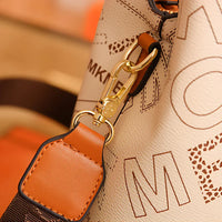 Close-up of a beige leather bag with gold hardware and orange-brown strap detail